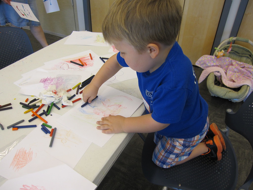 Child engaging in sensory play with crayons