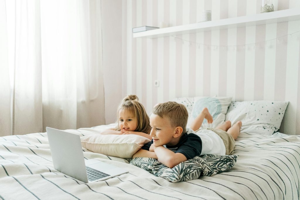 two children on the bed with their laptop