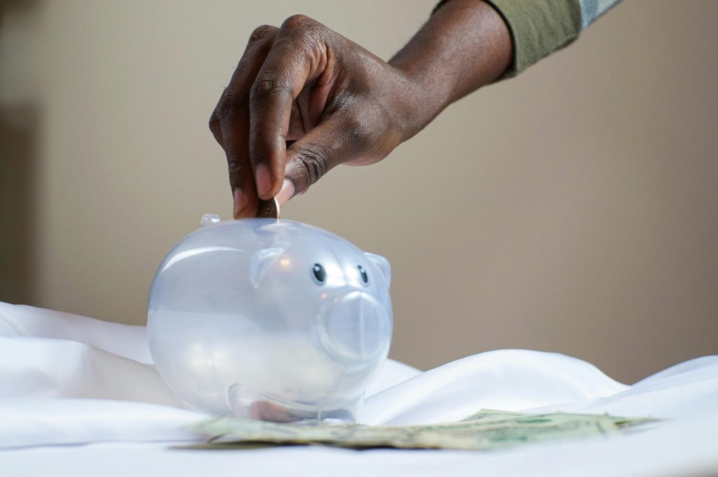 A hand putting a coin in the piggy bank